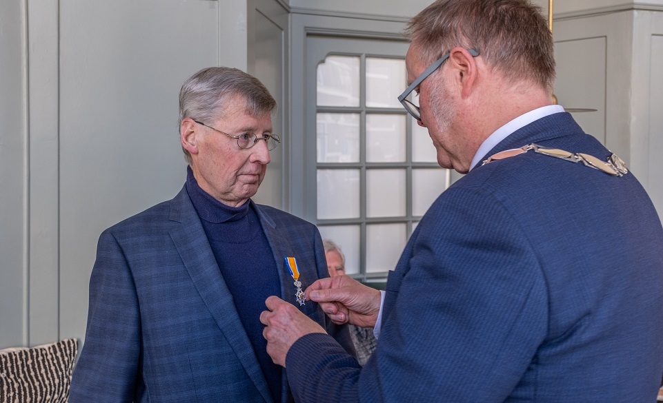 De heer Jan Scholten krijgt een koninklijke onderscheiding opgespeld door locoburgemeester Marcel Elferink.